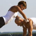 15178383-Couple-practising-on-the-early-morning-sun-Girl-doing-pushups-while-leaning-on-a-man-Stock-Photo-300x200